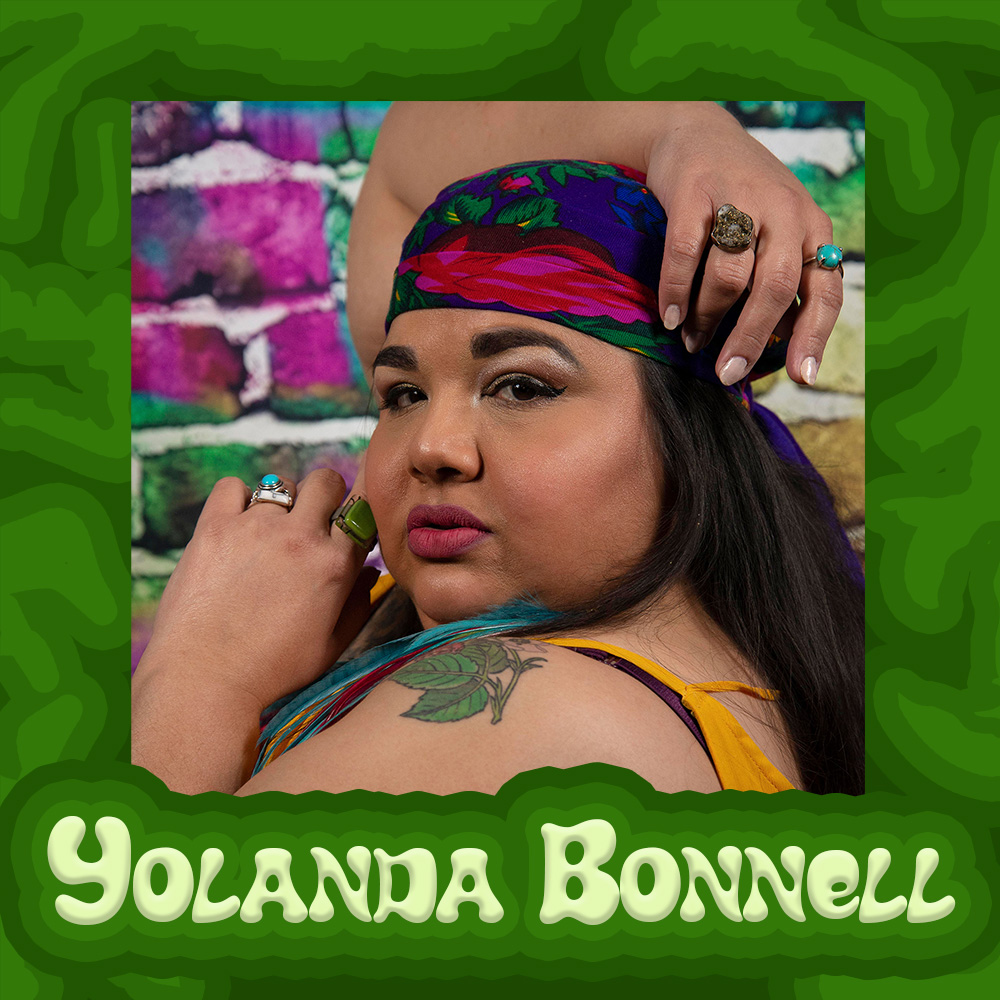 Photo of Yolanda Bonnell. Yolanda is a fat, brown skinned femme wearing a colourful scarf on her head and a yellow strapped shirt. She turns to look at the camera with her hands and arms visible. A tattoo of leaves is visible on her shoulder. Her picture is surrounded by a border of darker greens and her name in light green bubbly letters.