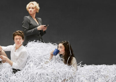 3 female government office workers surrounded by a large pile of shredded paper