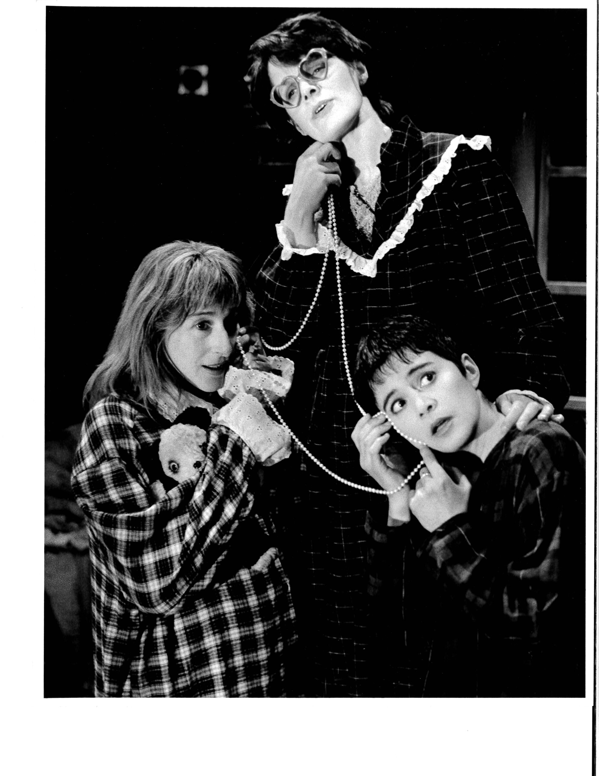 3 Women wearing long sleeved dark tops on the phone. All 3 phone cords are made of pearla and appear to be connected