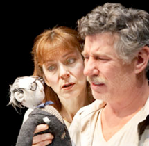 A man and woman stare at a puppet in confusion