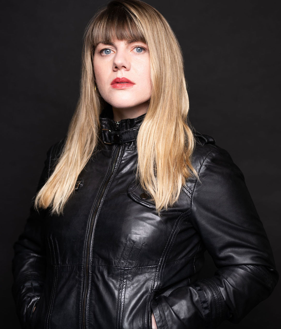Headshot of Derek Kwan. He is an East Asian man in his 40s, with a shaved head and stubble moustache and beard. He wears a white shirt, a dark green corduroy vest, and a dark grey suit jacket adorned with a needle-felted pin of a fox head.